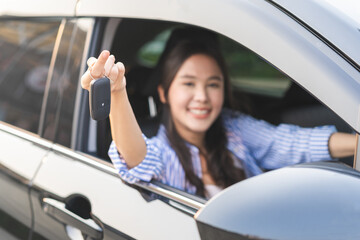 Dealership automobile, smile asian young woman, happy girl sitting in new car after purchase success, showing, holding auto remote key of vehicle, owner driver female buy gift for yourself at showroom