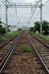 Fototapeta premium 雨の日の駅、曇り空の下に伸びた直線の線路 道のり・進路のイメージ