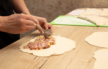 Preparing pizza dough with meat, onions and spices on wooden table