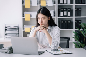 business woman sitting at her desk, reading stats and graphs on paperwork at the office.