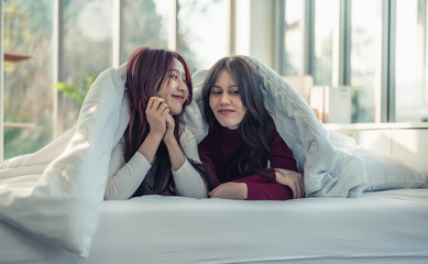 Asian lesbian couples are playing, smiling, relaxing, looking at each other under blanket in the bedroom. Every day, there are routine activities that need to be done at the beginning of the day.