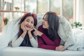 Asian lesbian couples are playing, smiling, relaxing, looking at each other under blanket in the bedroom. Every day, there are routine activities that need to be done at the beginning of the day.