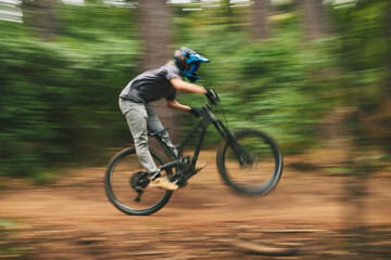 Fototapeta na wymiar Sports, bike and man doing adrenaline stunt with energy while riding fast for competition practice in woods. Fitness, blur motion and male athlete biker with training or exercise in an outdoor forest