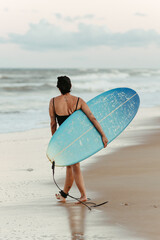 woman with surfboard on beach