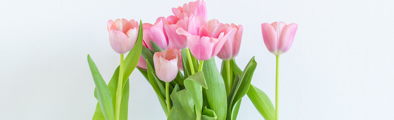 Naklejka premium Pink tulips bouquet in glass vase on white background copy space