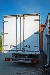 The truck is parked against the wall of the building on a summer day