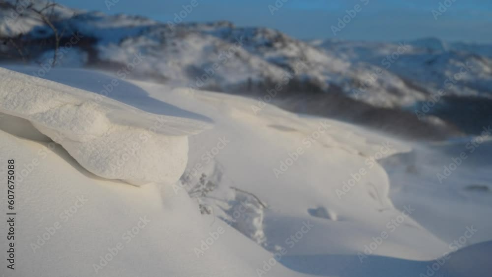 Poster macro closeup view of snow drifting blown across pile with mountains behind