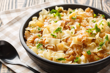 Austrian noodles with stewed white cabbage and caramelized onions close-up in a bowl on the table....
