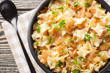 Krautfleckerl made of white cabbage, Fleckerl noodles, caramelized onion closeup on the bowl on the table. Horizontal top view from above