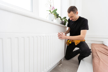 Repair heating radiator close-up. man repairing radiator with wrench. Removing air from the radiator