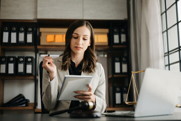 Beautiful Caucasian woman lawyer working and gavel, tablet, laptop in front, Advice justice and law concept. in office