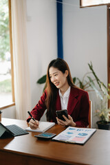  Beautiful Asian business woman typing laptop and tablet Placed at the table at the office..