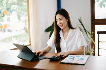 Asian woman working in the office with working notepad, tablet and laptop documents