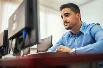 Fototapeta premium Male student using desktop PC in computer lab