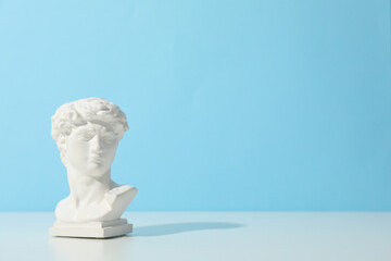 Ancient head on white table against blue background