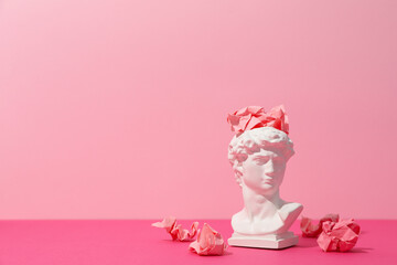Ancient head with paper balls on pink background