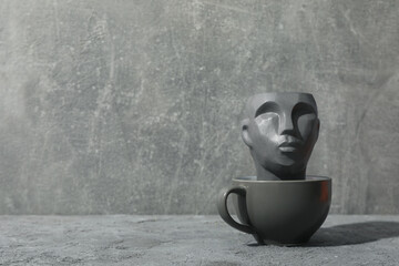 Cup with decorative head against gray background