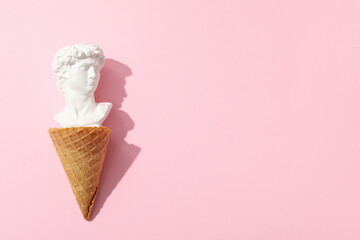 Waffle cone with ancient head on pink background