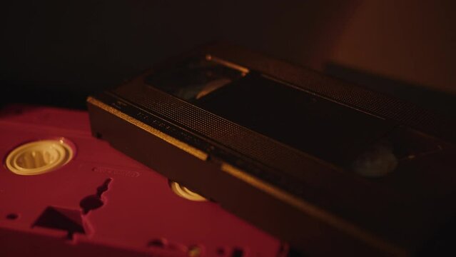 a stack of old video cassettes in the dim light of a lamp