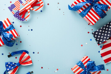 Celebrating Independence Day in the United States. Top-down view of emblematic party supplies: shimmering confetti, party glasses, necktie, bow-tie, gift boxes, blue backdrop with empty frame for text