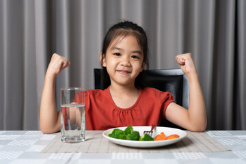 Kid shows strength of eats vegetables and nutritious food.