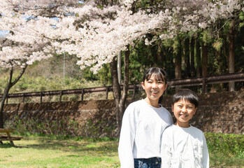 桜の下で記念撮影をする小学生の男女