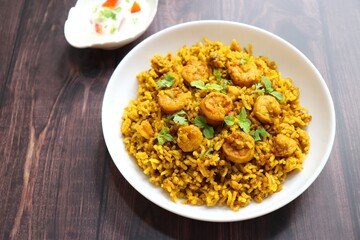 Prawns Biryani or shrimp Pulao. also called jheenga pilaf or jhinga biryani in India. known as Kolambi bhat in Marathi. Garnished with mint leaves, and coriander along with yogurt Raita. Copy space