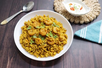 Prawns Biryani or shrimp Pulao. also called jheenga pilaf or jhinga biryani in India. known as Kolambi bhat in Marathi. Garnished with mint leaves, and coriander along with yogurt Raita. Copy space