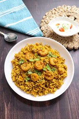 Prawns Biryani or shrimp Pulao. also called jheenga pilaf or jhinga biryani in India. known as Kolambi bhat in Marathi. Garnished with mint leaves, and coriander along with yogurt Raita. Copy space