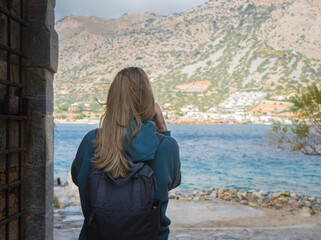 Attractive woman photographing Mediterranean scenery with cell phone, sea view, Crete Greece