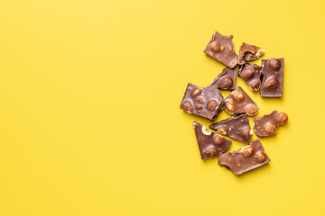 Chocolate bars with nuts on yellow background. Top view.
