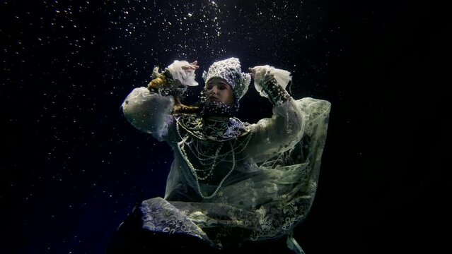 charming princess in old folklore dress swimming in dark deepness of magic sea or lake, underwater