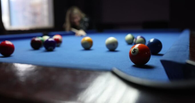 Player hits the red ball on blue pool table. Active player likes to play billiards on weekends
