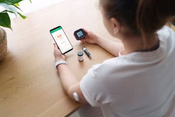 Woman with diabetes synchronizing smart phone and glucometer at home