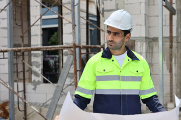 Caucasian technician civil engineer man or specialist inspector standing and planing real estate project work with blueprint while checking at Industrial building site. Construction concept