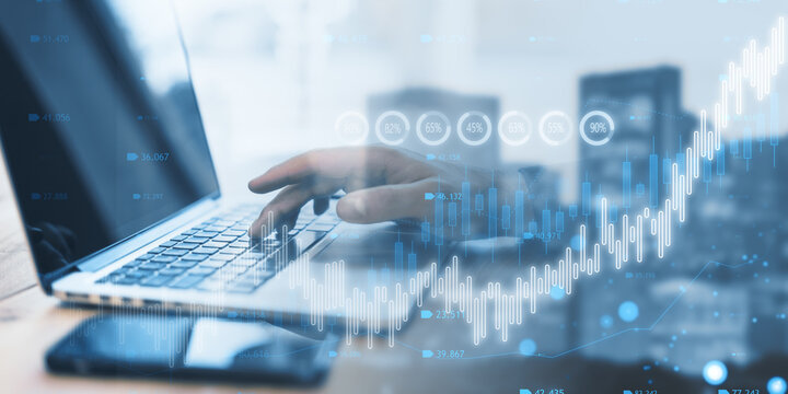 Close Up Of Male Hand Using Laptop With Creative Candlestick Forex Chart Or Graph On Blurry Wide City Background. Financial Trade Market And Stock Concept. Double Exposure.