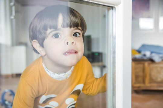 Naklejki Boy pressing nose against window