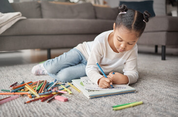 Young girl, kid and pencils on floor with coloring book in living room for education, learning or creative development. Cute child, books and crayons for writing, drawing or creativity of art project © L Ismail/peopleimages.com