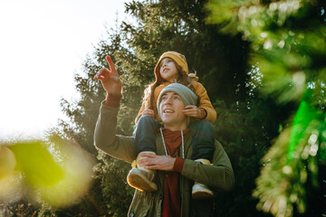 Father carrying daughter on shoulders in forest