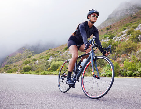 Road, woman and cycling with fitness, health and training for wellness, cardio and endurance. Female person, biker and cyclist with workout, street and practice with a helmet, glasses and exercise