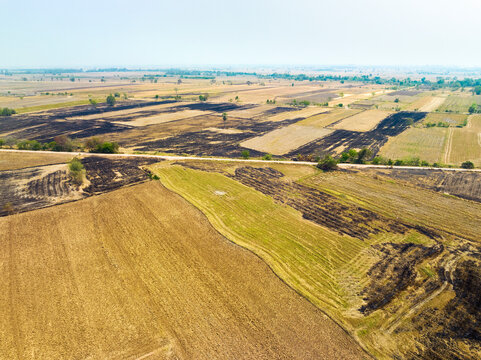 Aerial view of farmland with dry rice fields after harvest, partially burned down, Nakhon Luang, province of Ayutthaya, Thailand.