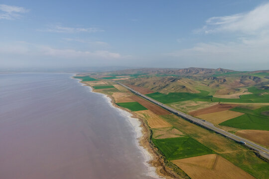 Aerial view of vehicles driving a scenic road along Lake Tuz (Tuz Golu), one of the largest hyper saline lake in the world, Central Anatolia Region, Ankara, Turkey.