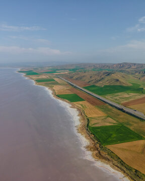 Aerial view of vehicles driving a scenic road along Lake Tuz (Tuz Golu), one of the largest hyper saline lake in the world, Central Anatolia Region, Ankara, Turkey.