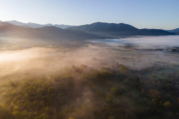 Aerial view of a valley with fog in early morning mist among mountains in Psaka, Epirus, Greece.