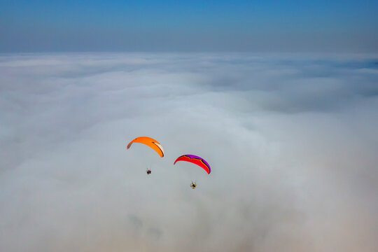Aerial view of two paramotors flying above fog and clouds on the Black Sea coast of Istanbul, Turkey.