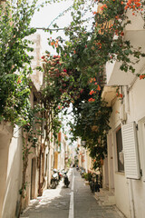 Fototapeta na wymiar Street view with old medieval historic buildings and flowers in small town in Greece, Crete. Traditional European, Greek architecture. Summer travel