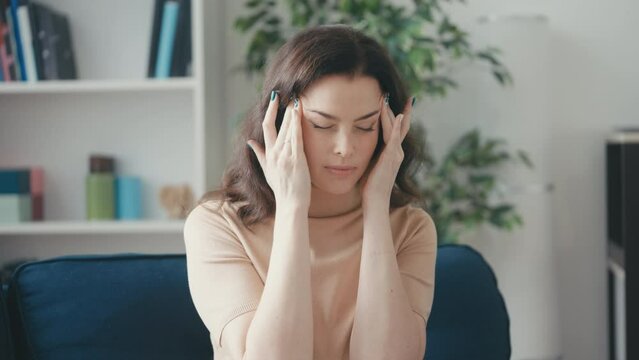 Middle-aged woman suffering headache, rubbing her temples, menopause symptoms