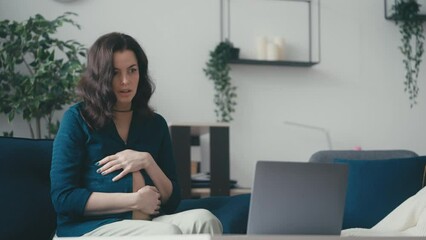Middle-aged pregnant woman watching childbirth video on laptop, feeling shocked