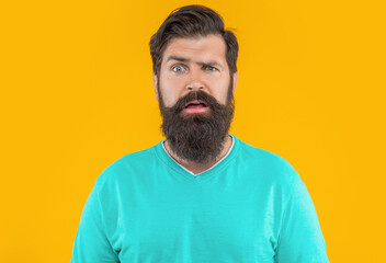 portrait of puzzled bearded man isolated on yellow studio background