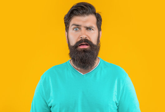 portrait of puzzled bearded man isolated on yellow studio background
